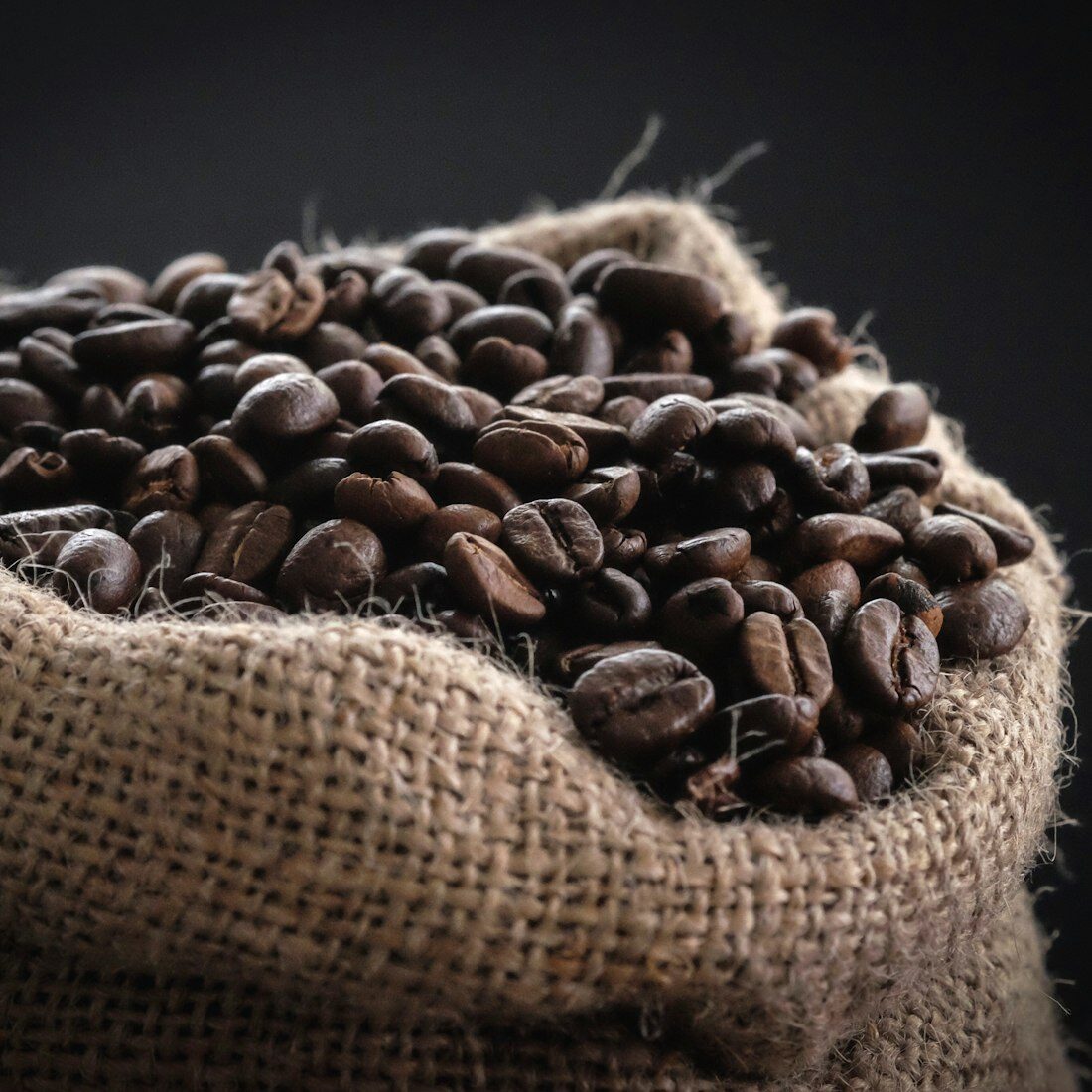 A hessian sack overflowing with freshly roasted coffee beans